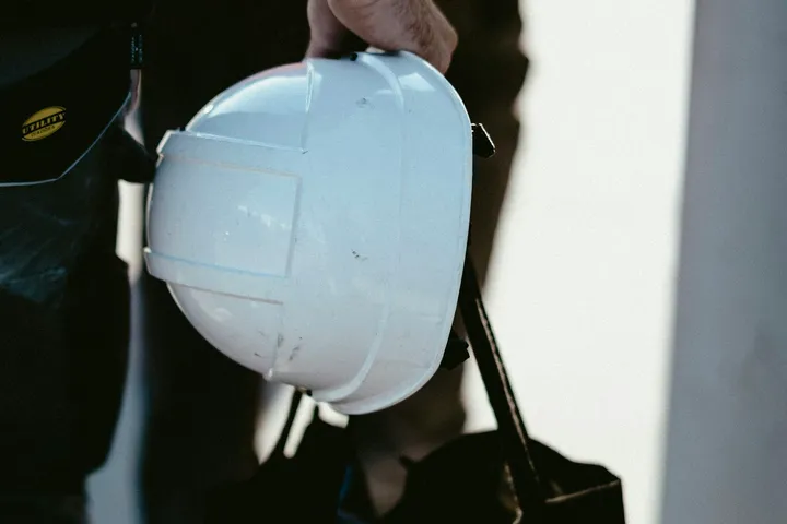 Trabalhador da construção a segurar um capacete de proteção